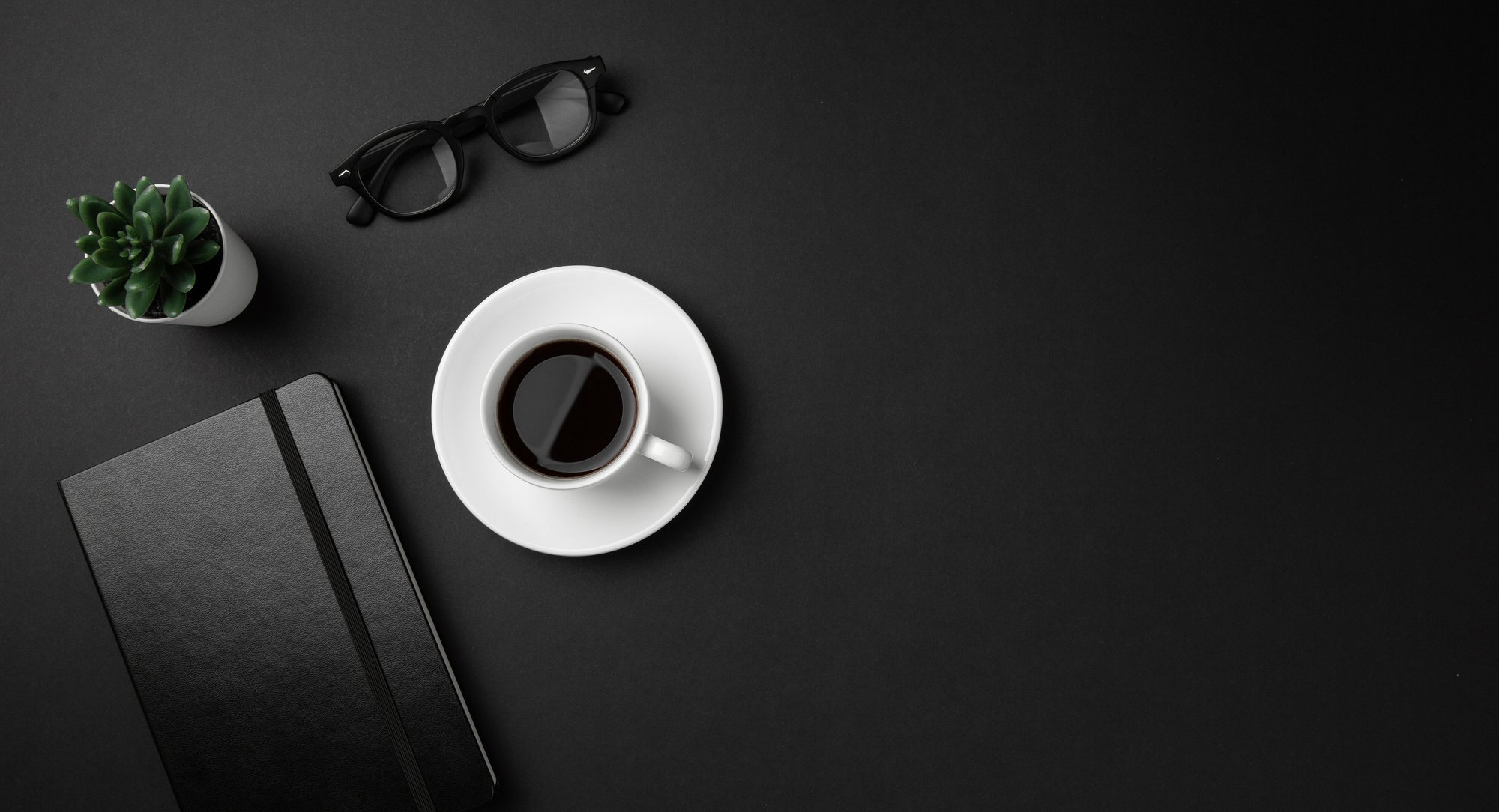 Black office desk top flat lay overhead view.